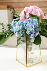Beautiful hortensia flowers in vase on white table indoors