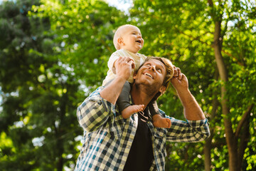 Obraz premium White father smiling while piggyback riding his son at park