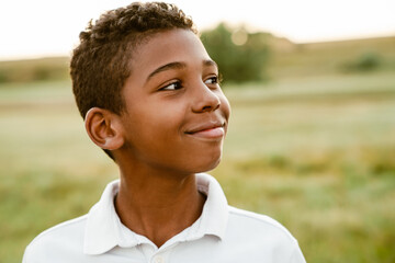 Black boy wearing white shirt smiling and looking aside
