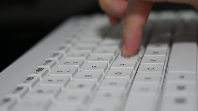 A man is typing on a bluetooth Logitech keyboard.