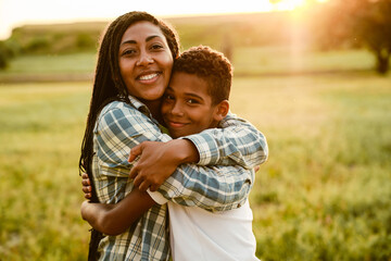 Black mother hugging her son and smiling on field