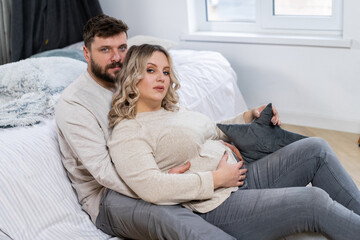 Happy family concept. Husband hug belly pregnant wife sitting floor indoor living room near sofa