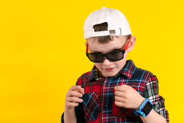 Cute fashionable kid boy isolated on yellow background.