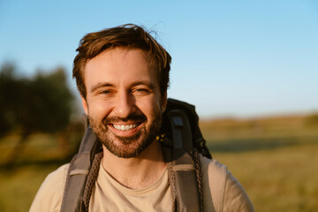 White bristle man with backpack smiling while hiking outdoors