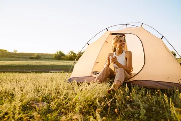 Keuken foto achterwand Kamperen White woman drinking tea while sitting in tent during camping