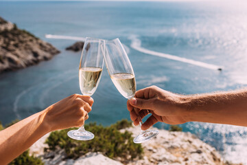 Hands holding champagne glasses over the sea. Romantic vacation. Two hands holding champagne...