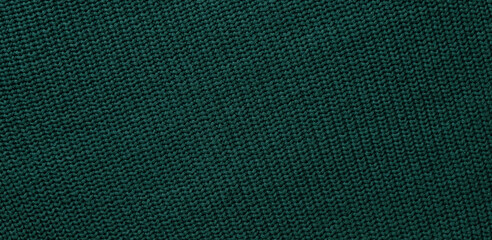 Texture of smooth knitted dark green sweater with pattern. Top view, close-up. Handmade knitting...
