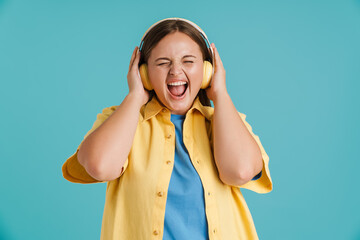 Young white woman screaming and listening music with headphones