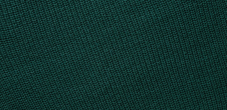 Texture of smooth knitted dark green sweater with pattern. Top view, close-up. Handmade knitting wool or cotton fabric texture. Background of Large Ribs knit pattern with knitting needles or crochet.