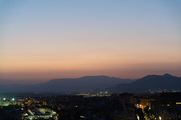 Aerial view of Granada, Andalusia, Spain at night. Urban city light in the foreground. Sierra Nevada mountain range with colorful sunset sky on the background.