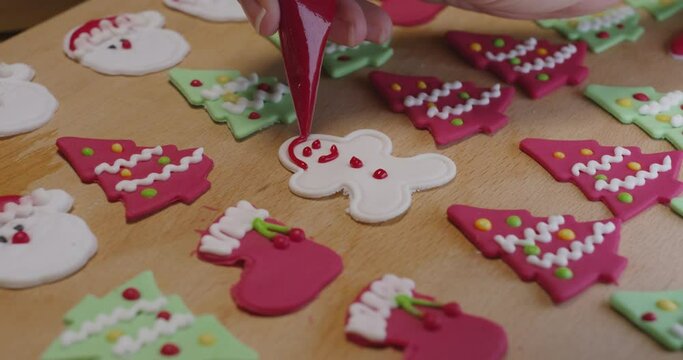 Close-up hand enjoy fun make craft gift party snack tasty cooking recipe on table in good warm relax time. Cute smile gingerman mold shape bakery royal icing sugar glaze with red green white color.