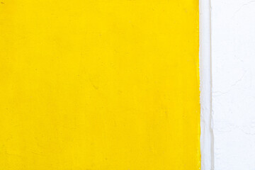 background of the cement wall is bright yellow and the white part is vertically separated. Color blocking two colors