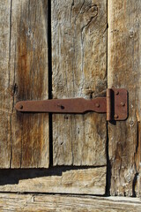 Wooden Fence Door View with Weathered Wall Planks, Old Rusty Hinges and Chains. Agricultural Livestock Building Tree Texture Background