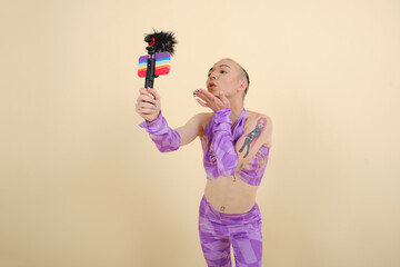Non-binary person sending a kiss to the mobile phone camera while streaming online or recording a video for a vlog.