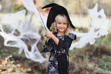 Beautiful girl witch. little girl in which costume celebrate Halloween outdoor and have fun. Kids trick or treating