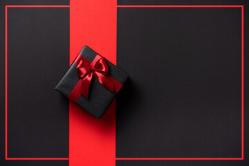 Black Friday, a stylish dark gift with a bow on a dark background with a place for text and a red...