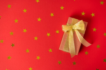 The gift is wrapped in gold paper with ribbons and a bow with stars on the background. Top view