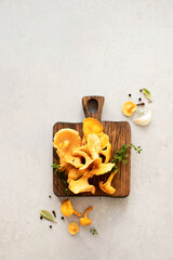 Chanterelle mushrooms on a wooden board with herbs and spices.