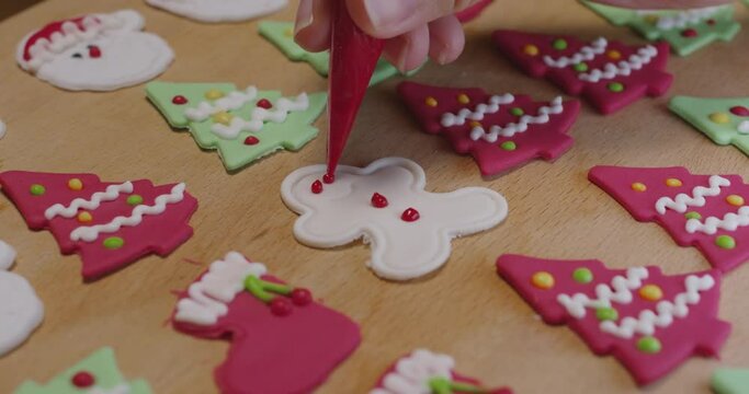 Close-up hand enjoy fun make craft gift party snack tasty cooking recipe on table in good warm relax time. Cute smile gingerman mold shape bakery royal icing sugar glaze with red green white color.