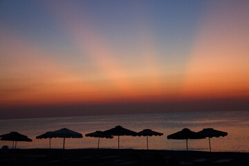 sunrise and silhouettes of umbrella from the sun on the background of the sea