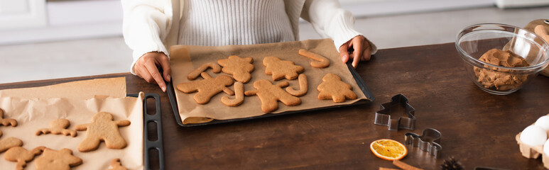 Cropped view of african american woman holding tray with christmas gingerbreads, banner