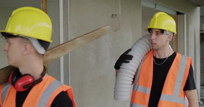People working in construction site. Clumsy and awkward man creating dangerous situation at work in new house. Two manual workers in funny moment inside building