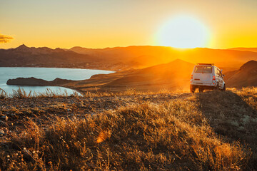 The jeep is standing on the top of the mountain in the sunset. A delightful landscape and the concept of travel, freedom and adventure © KseniaJoyg