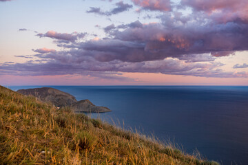 Stunning landscape on top of a mountain in the rays of sunset. Amazing view of the mountains and the sea coast, the concept of travel, freedom