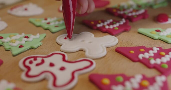 Close-up hand enjoy fun make craft gift party snack tasty cooking recipe on table in good warm relax time. Cute smile gingerman mold shape bakery royal icing sugar glaze with red green white color.