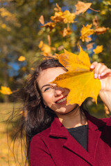 Portrait of a joyful young woman enjoying in the autumn park.