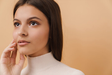 Young brunette woman touching her face and looking aside