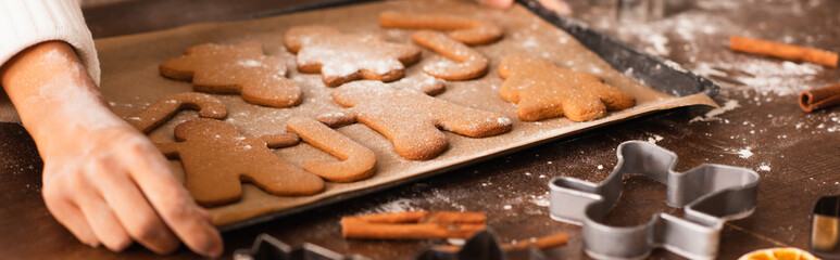 Cropped view of african american woman with hand in flour holding tray with christmas cookies and cinnamon, banner