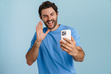 Young brunette man gesturing while using mobile phone