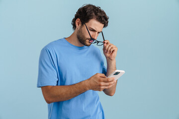 Naklejka premium Young brunette man in eyeglasses using mobile phone