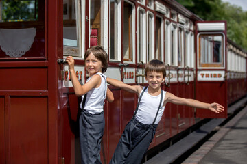 Beautiful children, dressed in vintage clothes, enjoying old steam train on a hot summer day