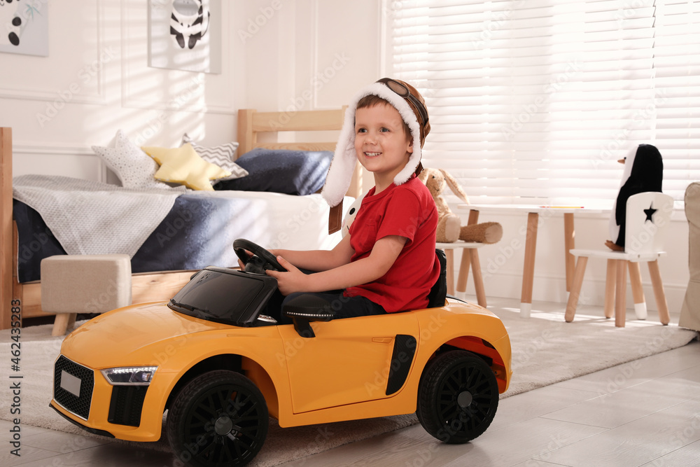 Poster Little child playing with toy car in room