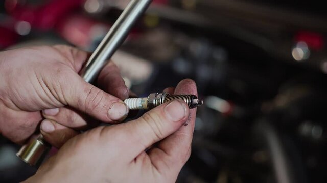 An auto mechanic replaces the spark plugs in the car