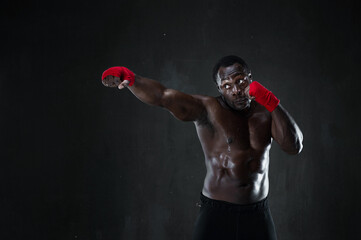 Sporty man during boxing training. Fitness african american muscular model over black background. Strength, fighting and motion project.