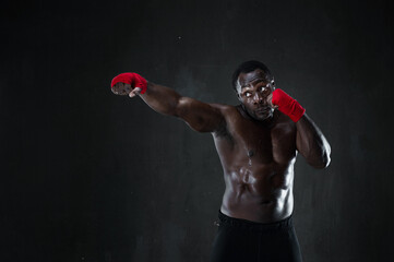 Sporty man during boxing training. Fitness african american muscular model over black background....