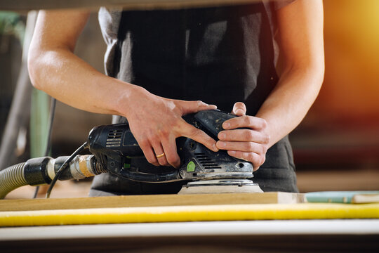 Cropped image of a craftsman grinding a wooden plank. No head, close up