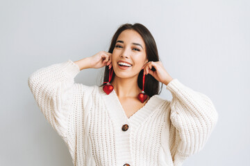 Young happy asian girl with long hair in white knitted cardigan with red heart christmas ball in...