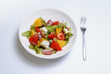 A bowl of fresh fruit and cheese salad on white background