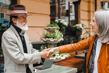 White senior couple holding hands and looking at each other in cafe