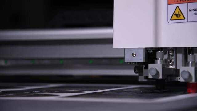 Industrial A close-up of an industrial plotter cuts a template on a cardboard packaging for products. real time shallow depth of field. Live camera