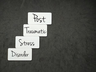 White wooden board with the letters ptsd and the words Post-traumatic stress disorder