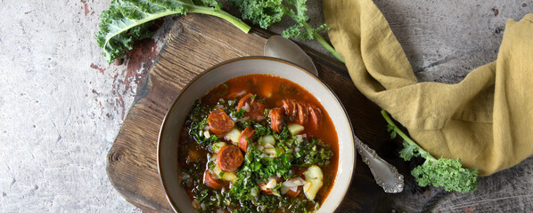 bowl of Portuguese caldo verde soup with kale and chorizo on the table - obrazy, fototapety, plakaty