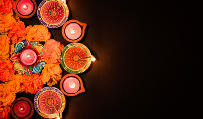 Happy Diwali - Clay Diya lamps lit during Dipavali, Hindu festival of lights celebration. Colorful traditional oil lamp diya on black background