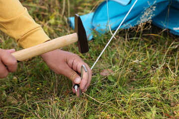 Man setting up camping tent outdoors, closeup