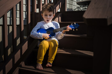 Little boy singing and playing the ukulele