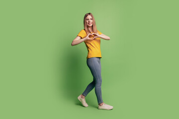 Fototapeta na wymiar Photo of lovely dream blonde lady show like symbol with fingers walk wear casual outfit on green background